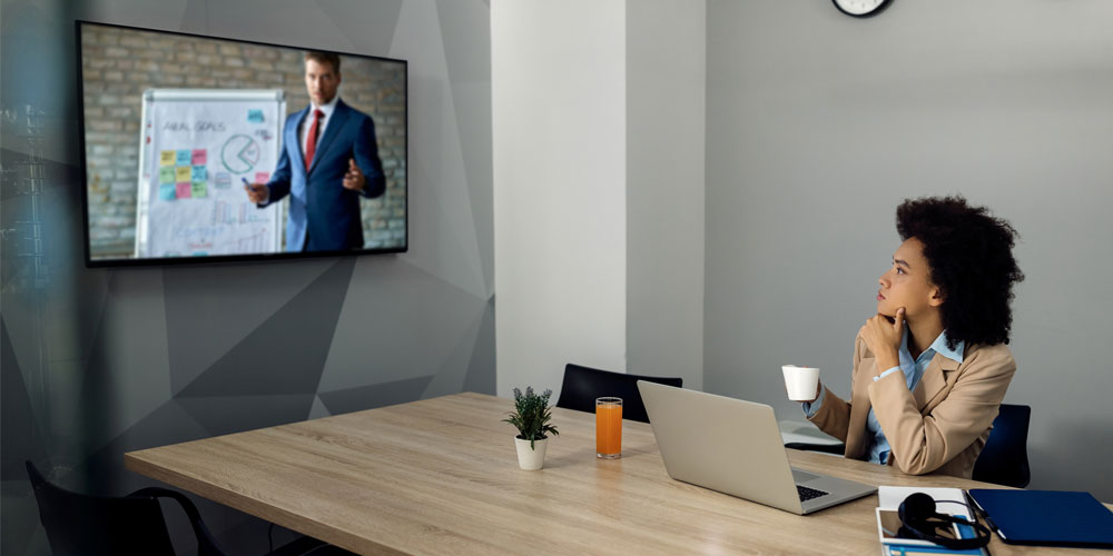 Corporate boardroom with dual displays, ceiling microphones and a video bar set up for a hybrid Microsoft Teams meeting